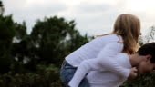 Slow motion of a young boy giving a young girl a spinning piggyback...