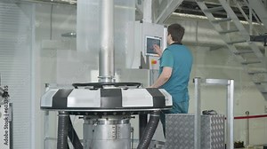 Plant worker sets up the automated machine using a control panel. Facility worker inserts the settings into the machine control panel. Worker selecting the machine mode from on a control panel.
