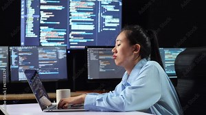 Side View Of Asian Female Programmer Being Bored Writing Code By A Laptop Using Multiple Monitors Showing Database On Terminal Window Desktops In The Office