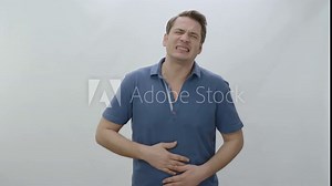 Man squeezing his stomach with his hands due to abdominal pain.A man with painful cramp in his sick, unhealthy stomach is squeezing his stomach and suffering from severe abdominal pain.
