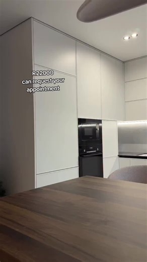 This kitchen island stands out with a commanding, sculptural design. Unlike a typical island, it's built with full-thickness black granite that wraps seamlessly around all sides giving it a bold, monolithic presence. What makes it even more distinctive is its double-sided functionality: part work zone, part serving counter. On the kitchen side, it features sleek handleless drawers that maximize storage while maintaining a clean, minimalist look. The stepped layout also helps to visually separate