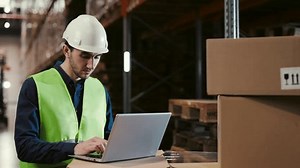 Efficient Employee at Cutting-Edge Logistics Center for a Global Online Retailer. Man Utilizing Laptop Computer to Enhance Order Optimization and Expedite Deliveries