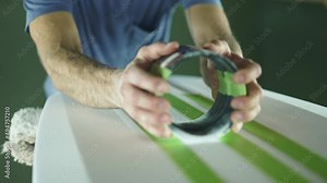 Surfboard making, shaper sands surfboard with sanding block. Concept of craftsmanship, small business in America, skilled professional in USA. Surfing industry.