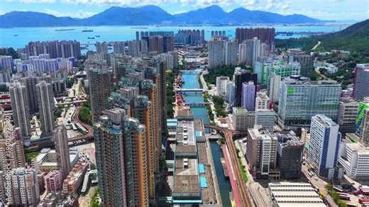 Aerial skyview of Tuen Mun subway extension project in Hong Kong, featuring elevated railway construction along Tuen Mun River and road, new station development and temporary work platforms
