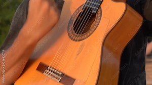 Man musician playing of a acoustic guitar on the beach at sunset in island Koh Phangan, Thailand. Male hands playing on the strings of a guitar, close up