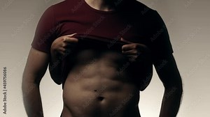 Female hands revealing abs of male slowly lifting up shirt