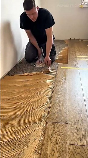 applying special adhesive glue on the floor surface and installing long wooden planks for flooring