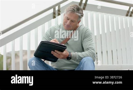Mature White male settling on landing sketching tablet with stylus reflecting before resuming work. Creative, reflection, urban, contemplative, minimalist, technology, inspiration Stock Video Footage - Alamy