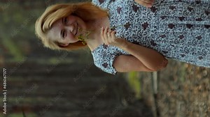 Trees in the forest form a perspective stretching into the distance and romantic girl in a summer sundress walking in the forest enjoying life vertical