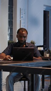 Vertical video: Diverse colleagues working in team to plan online presentation, analyzing data on laptop. Doing teamwork collaboration to create startup report with financial shares. Handheld shot.
