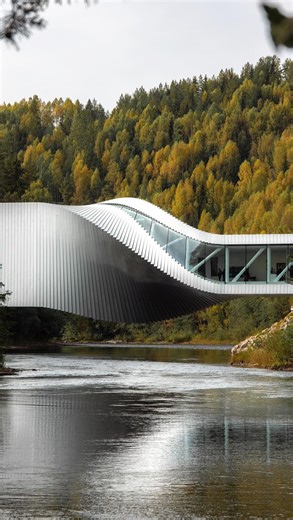 @art on Instagram: "The Twist is a striking hybrid structure that functions as both a bridge and an art museum. Architecturally, it blends engineering precision with artistic expression—constructed from sleek aluminum panels and glass, with a light-filled interior gallery that adapts to the twist’s changing geometry. The structure connects the forested landscape on either side of the river and is designed to offer varied perspectives as visitors move through it. Inside, the museum features three