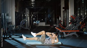 Sportsman doing twist sit-ups abdominal crunches lying on a floor mat in gym
