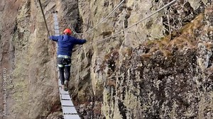 Man in body harnesses feature life-safety, attaches hooks to iron brackets, climbs rock, active lifestyle of people, mountaineering, viaferrata in mountains of pyrenees, High quality 4k footage