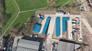 Aerial drone footage of a collection of large blue shipping containers in the town centre of Armley in Leeds West Yorkshire in the UK showing the large metal storage bins from above