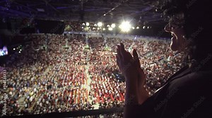 Young hispanic woman give a standing ovation applauding to the performers on stage