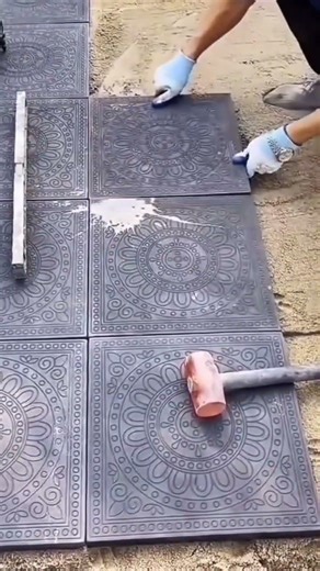the process of installing decorative patterned square tiles on the front yard of a house #popular