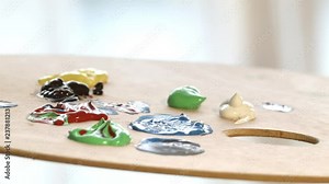 Applying blue paint on palette to a brush. Close detail shot.