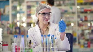 female scientist Experimenting through tubes of chemical liquids and plant samples. In a laboratory with test samples in the background in a modern laboratory By testing safely and cleanly.