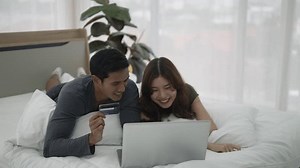 clip-3454460447-young-couple-use-laptop-bedroom-lifestyle