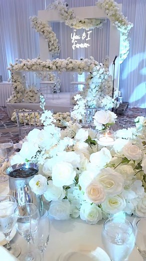 Wedding decor features stunning white rose arrangements, enchanting floating candles, and a head table draped in cascading flowers. The wrap-around floral backdrop adds a touch of romance and elegance to this unforgettable celebration. #WeddingPlanner #EventDesign #FloralDreams #RomanticWedding #LoveInBloom #weddingınspo #weddingbackdrop #weddingdecor #weddingdesign #weddingideas #weddingvenuedecor #weddingstagedecor #chicagopartydecorator #chicagobackdrops #chicagopartyrentals #chicagoeventplan