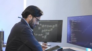 Focused Indian male AI developer coding a complex machine learning algorithm late at night. A dedicated data scientist working on a neural network at a multi-monitor workstation.