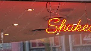 This panning video shows a classic neon sign in a restaurant window that says "shakes"
