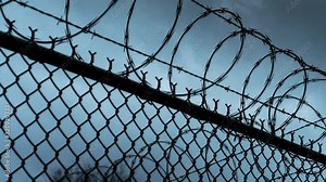 Time-lapse of prison razor wire and barb wire border perimeter.