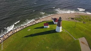 Lighthouse beacon across ocean aerial view tilt up to reveal horizon
