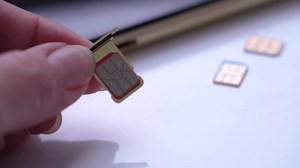 Person inserting a sim card into back of mobile phone, Sim card in tray being inserted into phone, closeup