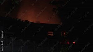 Night scene of fire engine with emergency lights at burning building.