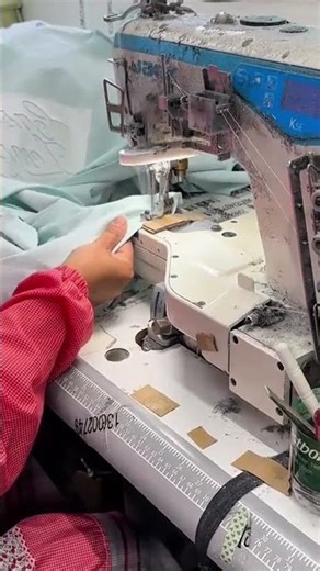 sewing intricate white patterns onto a light blue fabric using an industrial sewing machine