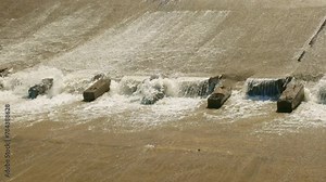 row of chute dentate blocks in concrete water spillway channel slope slowing down the flow of water running down.