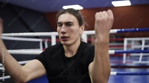 Handhelded footage of a male boxer warming up. Twisting his body,waving hands, holding hands before face. Training process. Boxing gym