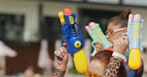 Stylish Young Girls in Bikinis Dance Near the Pool Holding Water Guns in Their Hands
