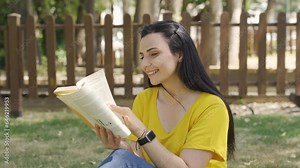 Cultured and intellectual woman reading a book in the park.