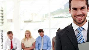 Interviewer smiling at camera in front of applicants