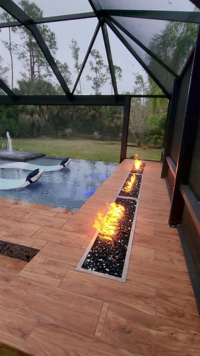 We design and build some insane modern pools. This backyard features an elevated sun shelf with ledge loungers, a swim-up bar, fire features, an outdoor kitchen, a sunken living area, a fountain wall, and a screened enclosure. #insanepools #lucaslagoons #modern