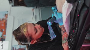 Tattooing process in a tattoo studio - Focused tattoo master doing a tattoo sketch. Vertical social media. High quality 4k footage
