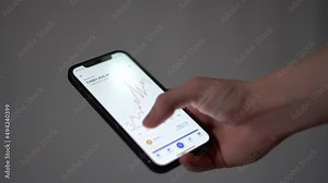 Checking bitcoin graph charts on mobile phone smartphone app coinbase to earn profit trading crypto currency - Investing on mobile phone app with white background looking at charts