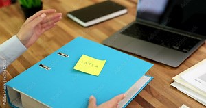 Accountant employee sticks sticker with inscription later on business folder with documents. Deadlines on demand for deferred signing