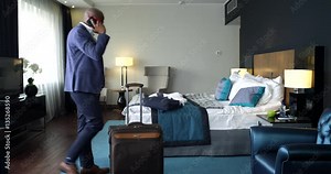 The Business Call in a Hotel Room/Afro-american businessman walks around the hotel room while talking on the phone