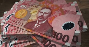 New Zealand dollar 100 NZD banknotes falling on the table. New Zealand currency paper notes count on stack. Timelapse of money counting. 3D concept.