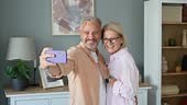 Cheerful mature couple taking selfies at home