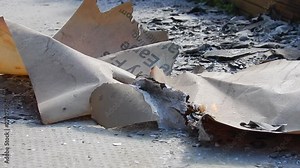 Concept explosion, disaster, accident, Burning & smoking official documents on pavement, sidewalk surface, blowing in the wind. Destruction close up blast explosion..