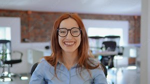 flirty employee with red long hair and eyeglasses happy smiling showing hand gesture air kiss looking at the camera. portrait young caucasian businesswoman sitting at the workplace in modern office. Stock Video