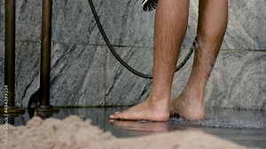 4K 50fps, Close-up of a pair of feet, washing feet, using a shower to clean water, and rubbing the other foot to make it more clean.