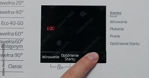 Selective focus on hand selecting laundry settings on state-of-the-art digital display. Close-up view of automatic washing machine with touchscreen on control panel. Girl presses start or pause.