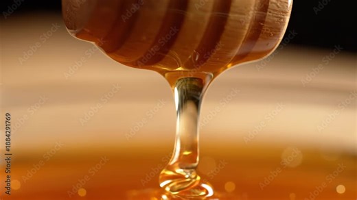 Golden honey dripping from wooden honey dipper in three stages on a warm surface