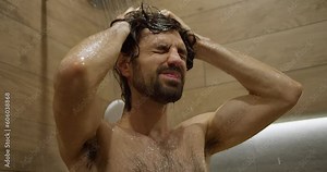 Close-Up of Dark-Haired Male Washing Hair and Face in Modern Shower, Frontal View