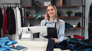 Beautiful woman dressmaker smiling at workplace electric sewing machine textile at tailoring atelier